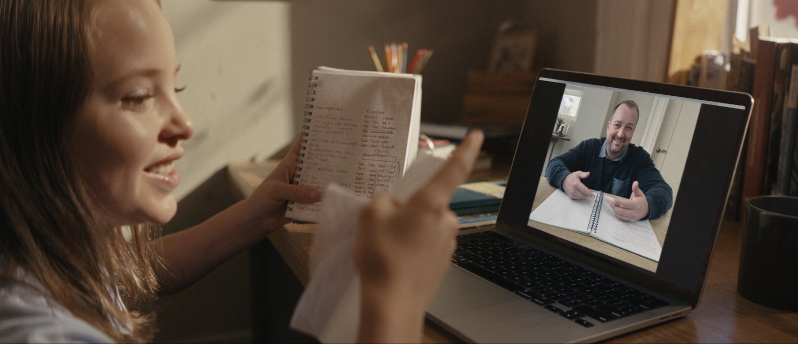 A student showing her notebook to her mentor on a live video call from home